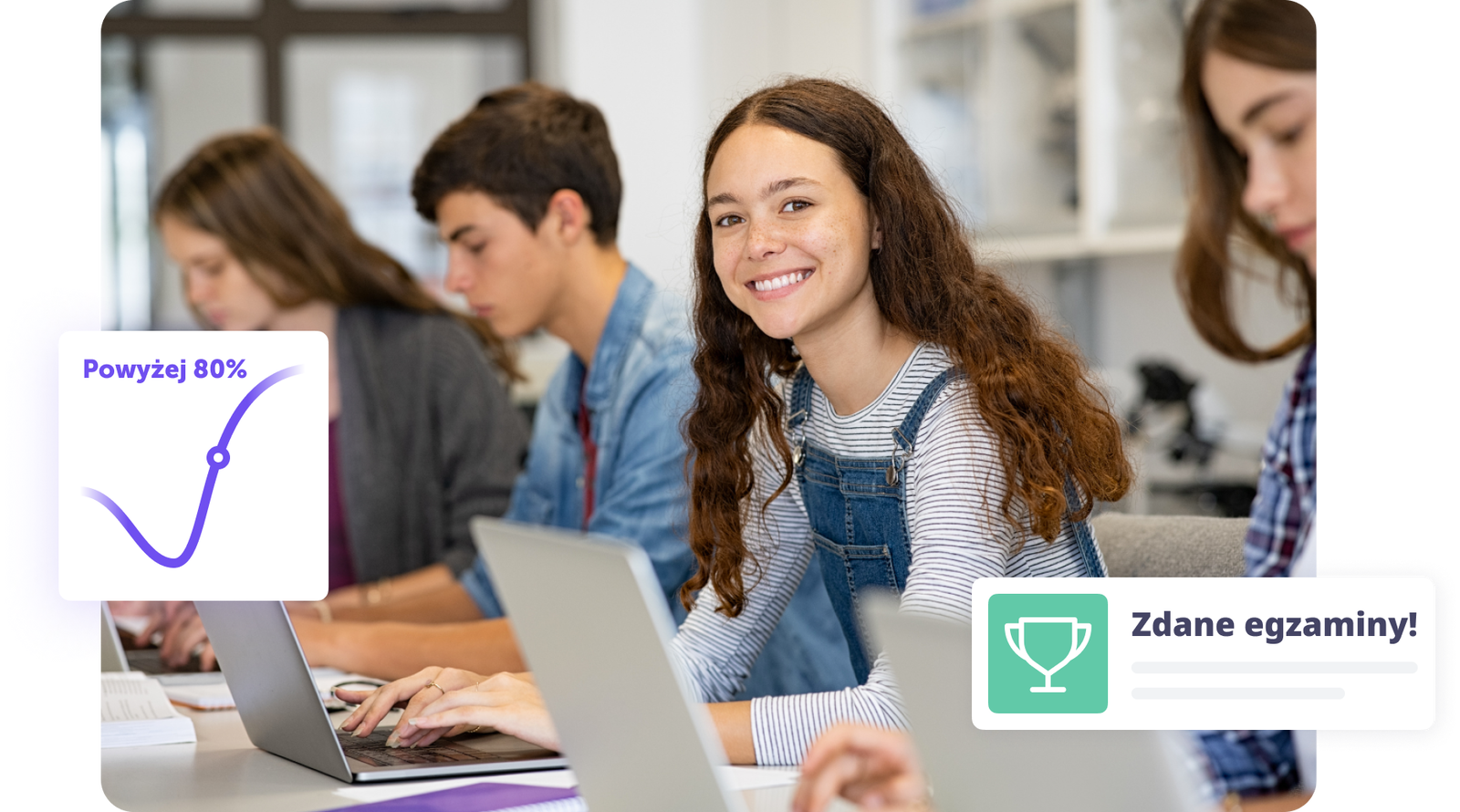 Uśmiechnięta uczennica pracująca na laptopie w klasie z innymi studentami.
