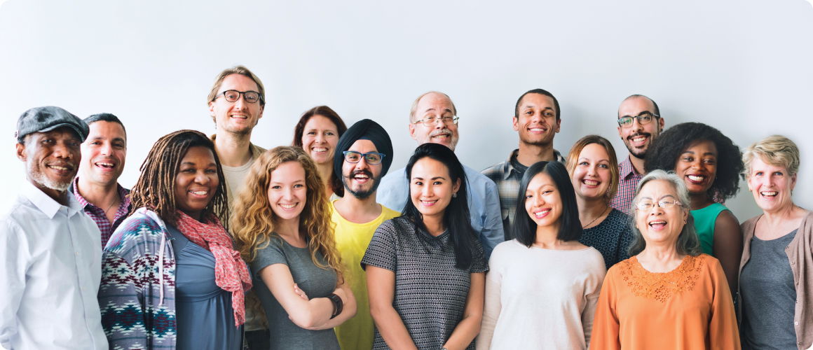 Attēlā redzama daudzveidīga, smaidīgu komandas locekļu grupa gaišā biroja telpā, kas simbolizē sadarbību, komandas darbu un pozitīvu darba vidi.