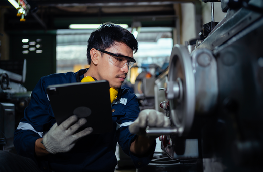 Industrial technician inspecting and adjusting machinery during maintenance.