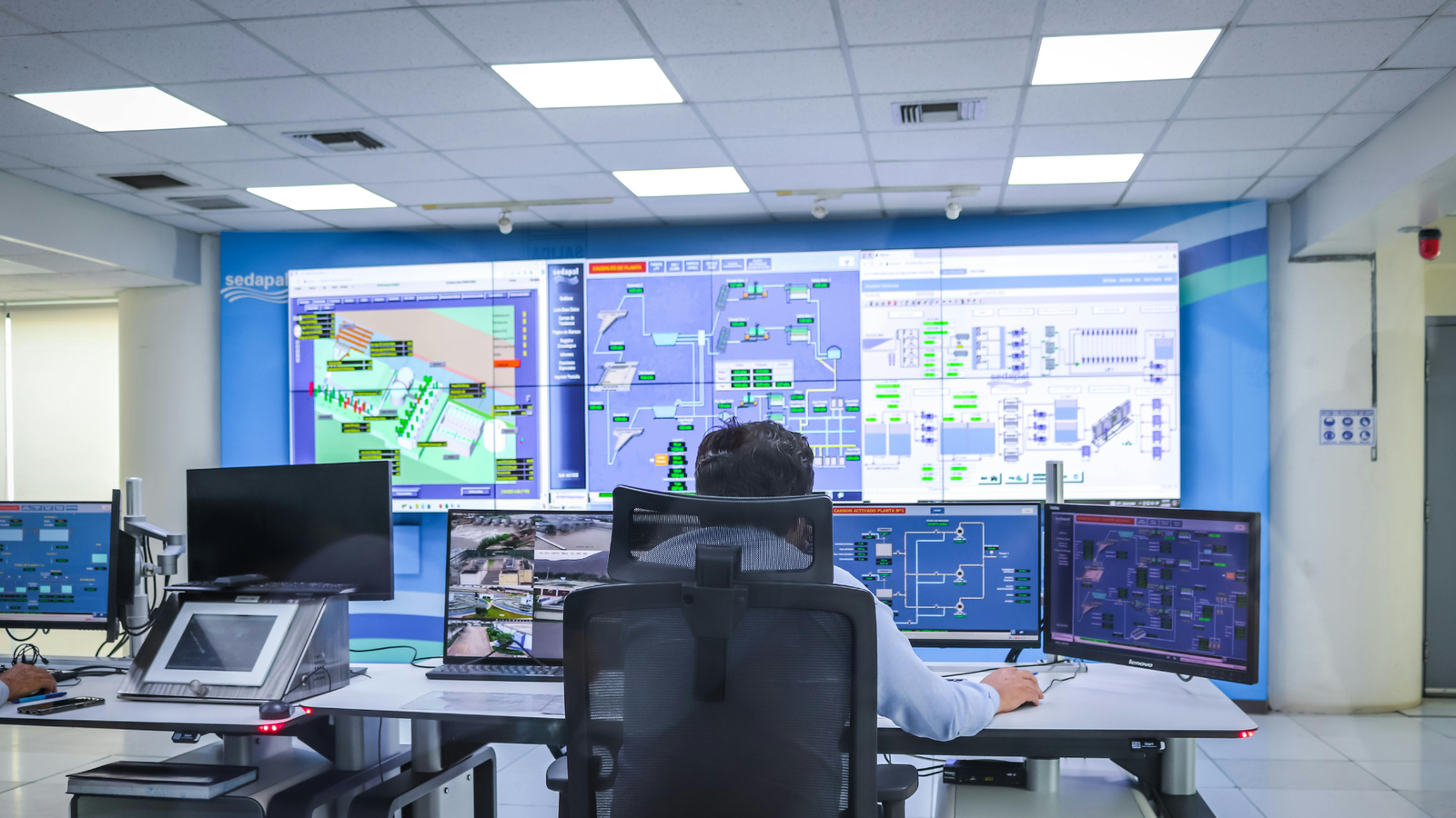 Operator monitoring industrial control systems and SCADA dashboards in a control room.