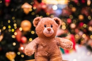 A teddy bear in the foreground with a bright Christmas decor background