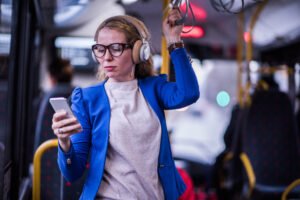 Business woman listening music in public transport.