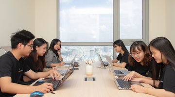 Six people sitting at table using laptops