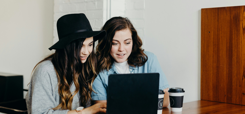 Two women sitting in front of a table where a computer is placed