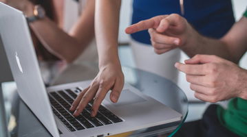 People pointing at a laptop screen.