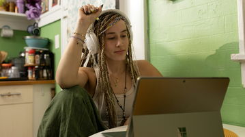 A woman with dreadlocks sitting in front of a laptop.