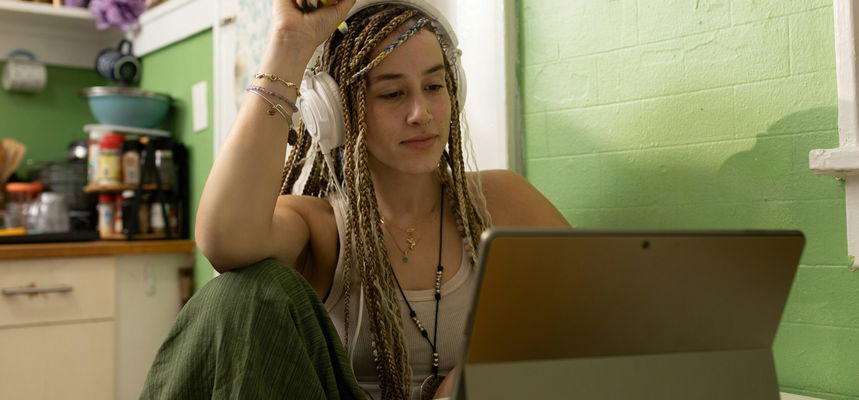 A woman with dreadlocks sitting in front of a laptop.