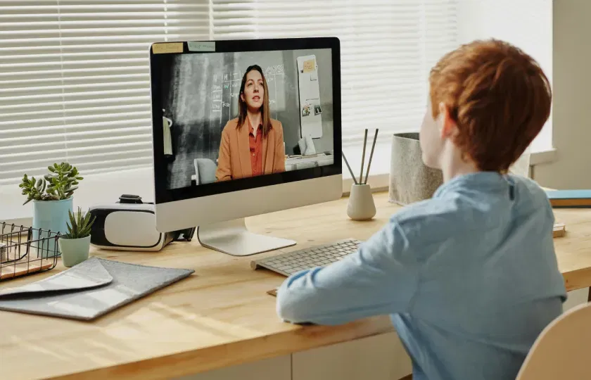 A child sitting by the table while looking at the iMac. What the European Accessibility Act means for e-learning