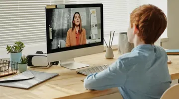 A child sitting by the table while looking at the iMac. What the European Accessibility Act means for e-learning