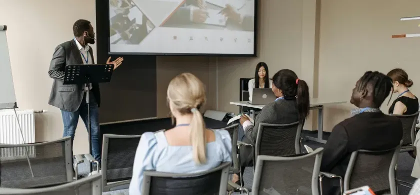 Man in black blazer having a presentation in front of employees demonstrating universal design for learning (UDL) principles for workplace training