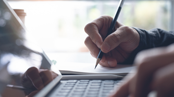 A hand is holding a pen and writing.