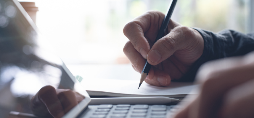 A hand is holding a pen and writing.