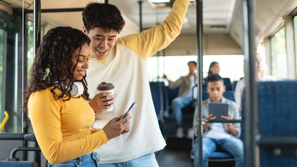 Two people are looking at a smartphone on a bus.