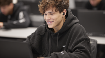Student with headphones working on a computer.