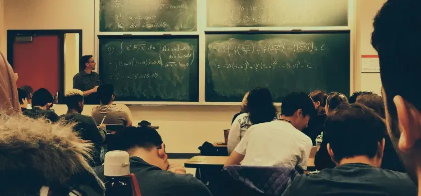 Students sitting on chairs in front of chalkboard - Bridging the accommodations gap in K12 and higher education