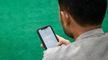 A man reading an arabic text message on his phone.
