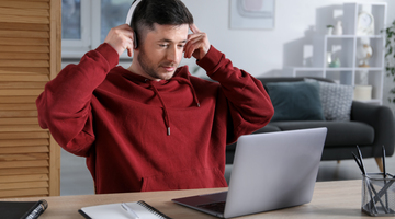 Mann mit Kopfhörern, der einen Laptop benutzt.