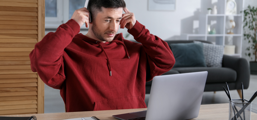 Mann mit Kopfhörern, der einen Laptop benutzt.
