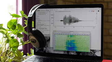 An open laptop showing soundwaves, representing spoken audio.