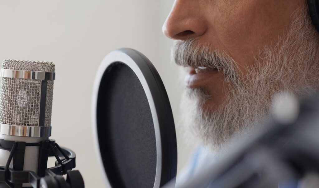 Close-up of a voice recording session with a studio microphone and pop filter.