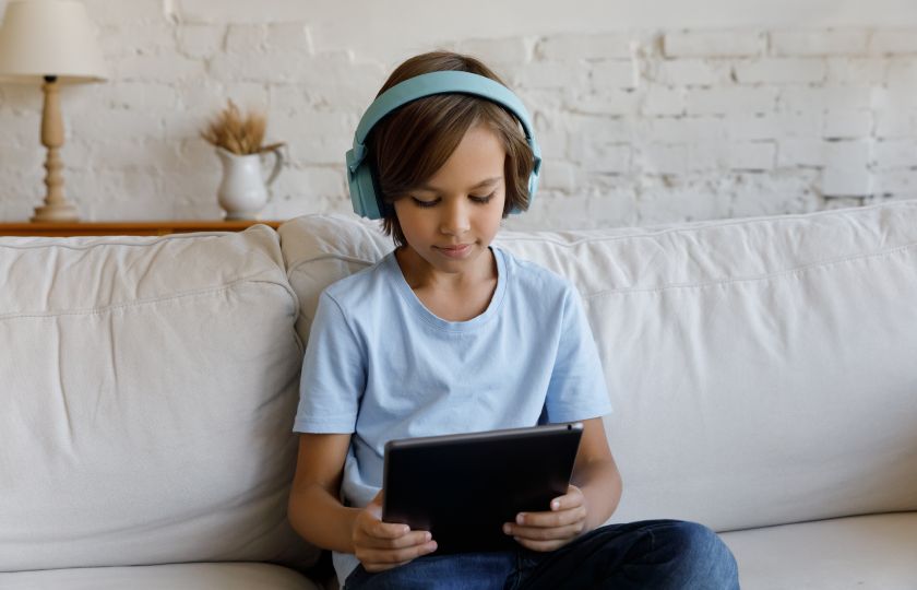 Un niño con auriculares escucha en su tableta un texto leído en voz alta