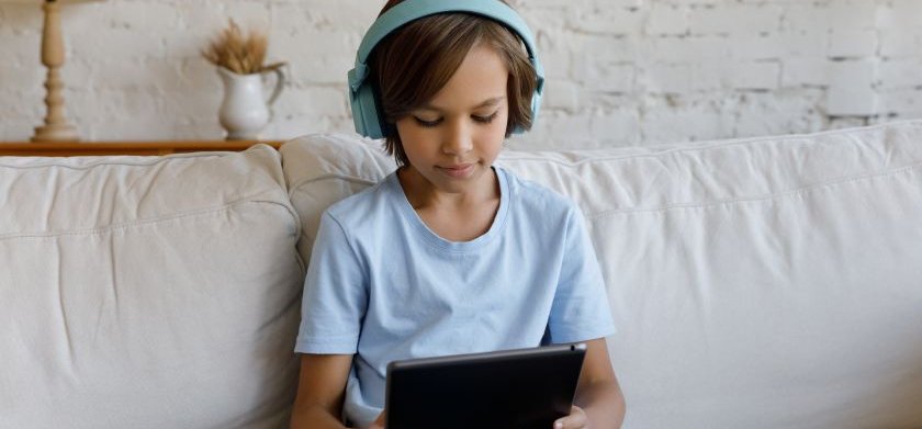 Un niño con auriculares escucha en su tableta un texto leído en voz alta